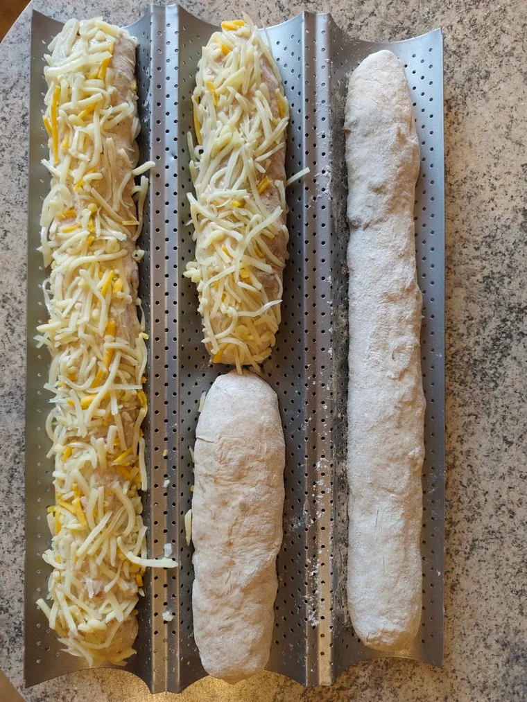 Röstzwiebel- und Schinken-Käse-Baguettes vor dem Backen auf einem Baguetteblech